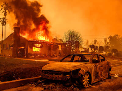 The carcass of a burnt-out car is seen as home burns during the Eaton Fire in the Altadena area of Los Angeles County, California, on January 8, 2025.