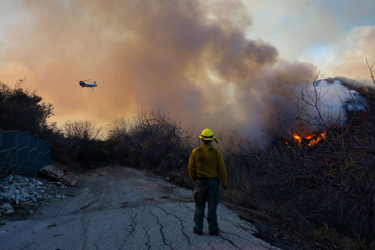 A firefighter watches a helicopter fight a wildfire