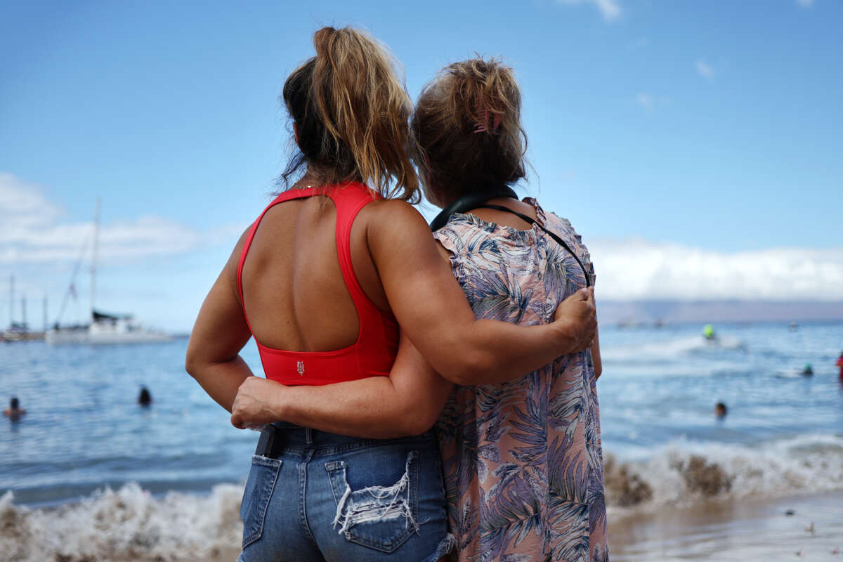 Two people embrace as they look out over the ocean