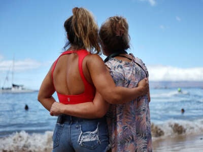 Two people embrace as they look out over the ocean