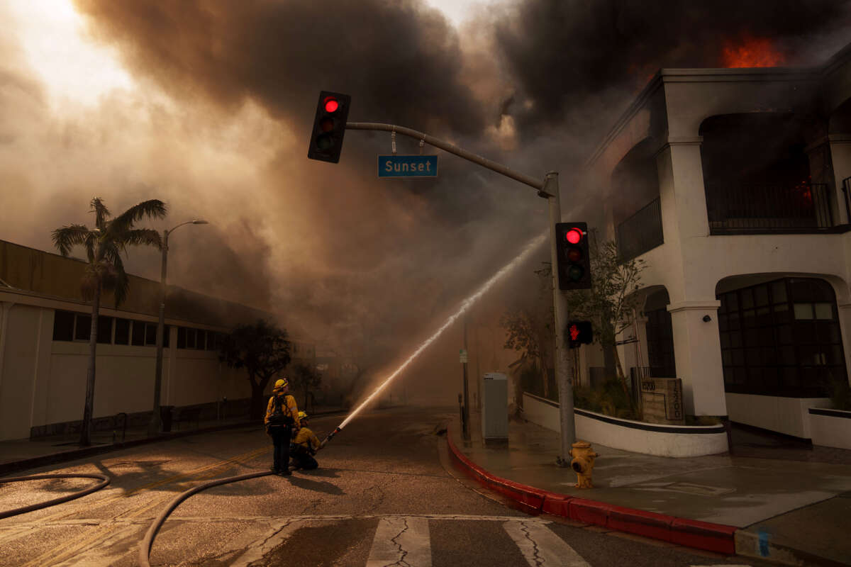 Firefighters spray flames from the Palisades Fire burning a business on January 8, 2025, in the Pacific Palisades neighborhood of Los Angeles, California.