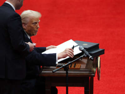 President Donald Trump signs executive orders during an indoor inauguration parade at Capital One Arena on January 20, 2025, in Washington, D.C.