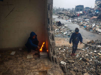 Palestinian children light a fire to warm up in a damaged building amidst rubble on a rainy day in Bureij in the central Gaza Strip on January 23, 2025, days into a ceasefire deal in the war between Israel and the Palestinian Hamas movement.