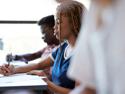 Students write at their desks in a classroom.