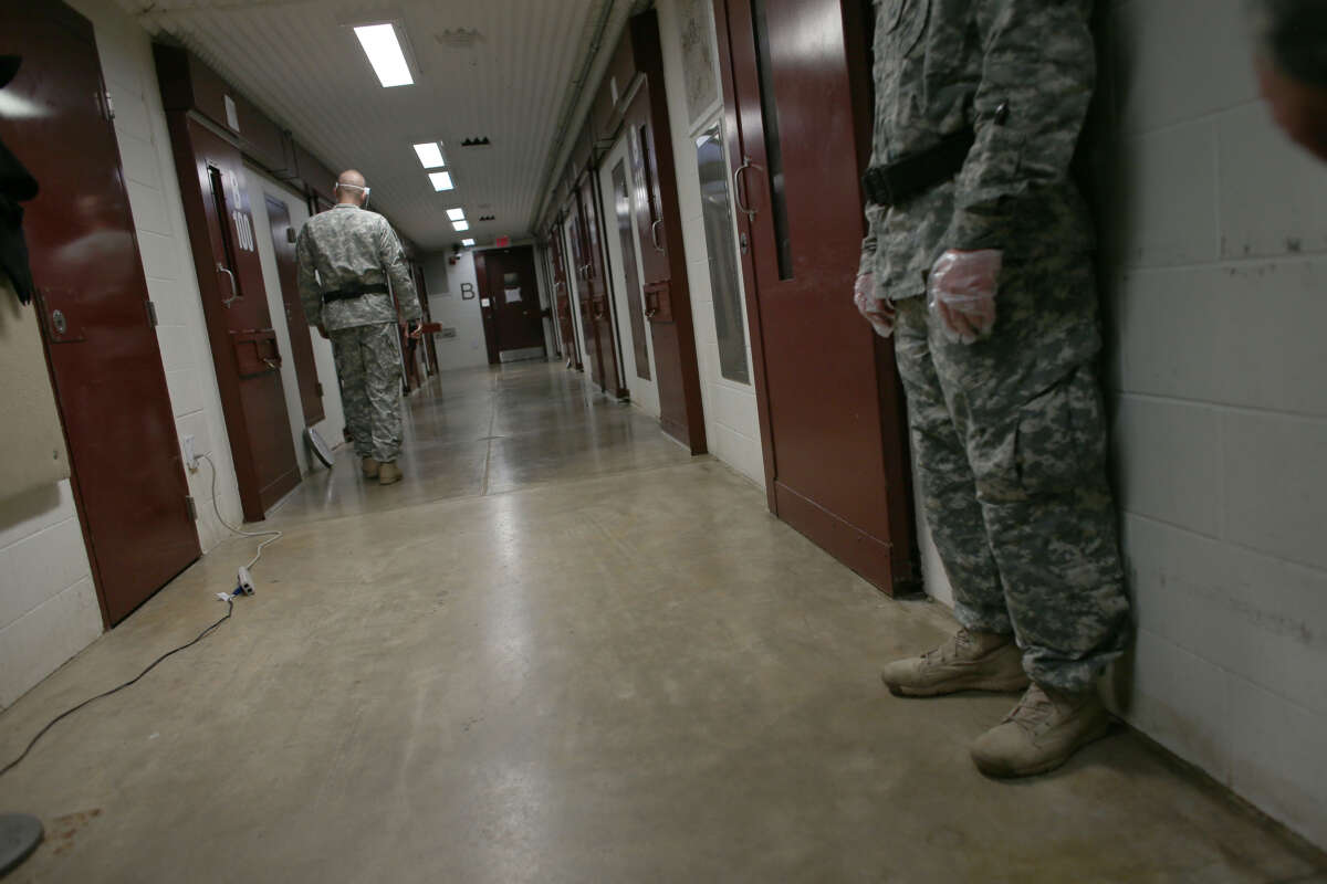 U.S. Army Military Police walk through a cell block during morning prayer at Camp V in the U.S. military prison for 'enemy combatants' on June 26, 2013, in Guantánamo Bay, Cuba.