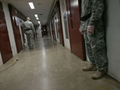 U.S. Army Military Police walk through a cell block during morning prayer at Camp V in the U.S. military prison for 'enemy combatants' on June 26, 2013, in Guantánamo Bay, Cuba.