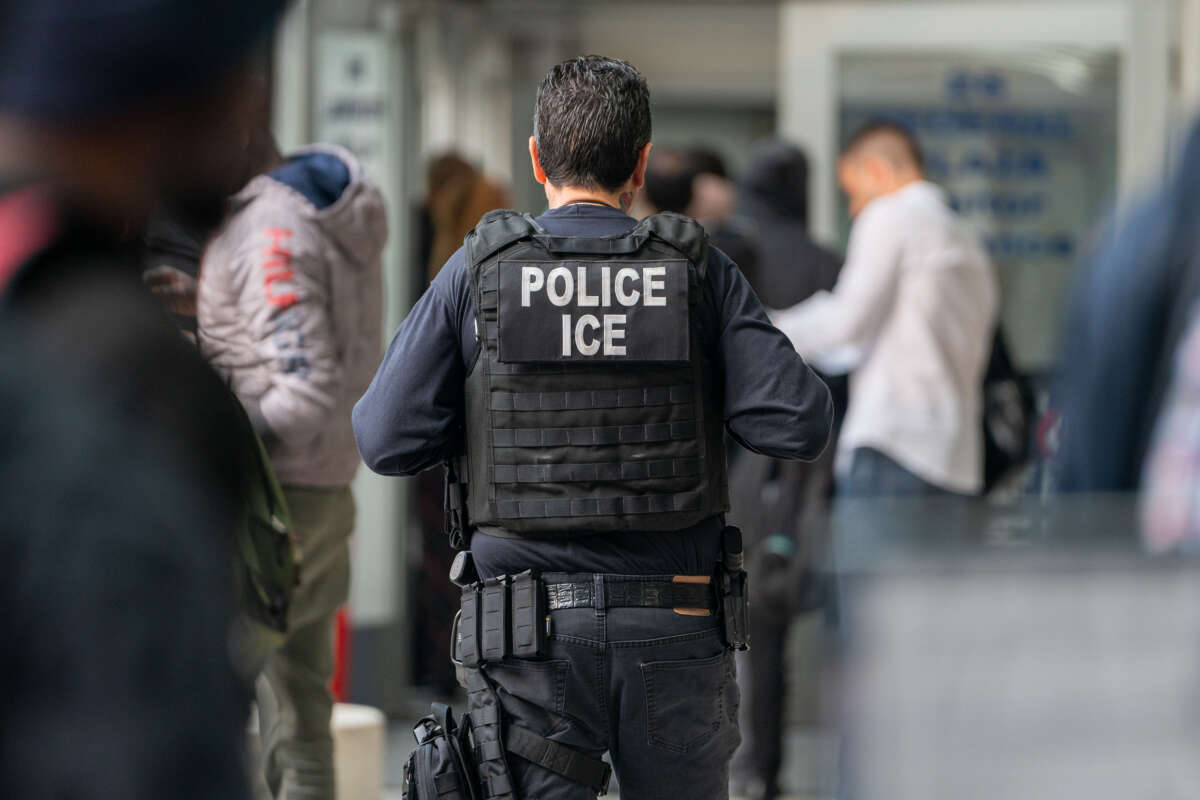 An ICE agent monitor asylum seekers being processed upon entering the Jacob K. Javits Federal Building on June 6, 2023, in New York City.