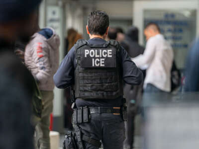 An ICE agent monitor asylum seekers being processed upon entering the Jacob K. Javits Federal Building on June 6, 2023, in New York City.