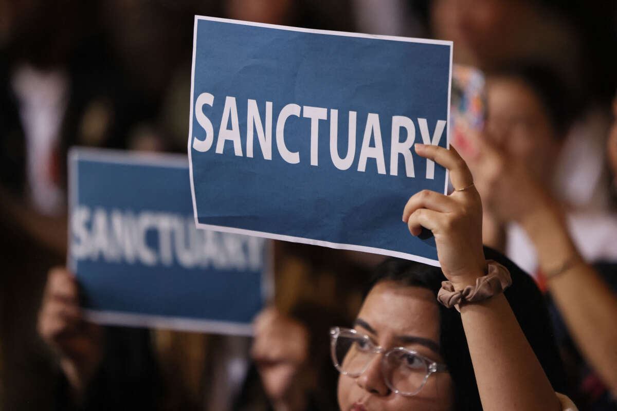 People in the audience hold up signs as the Los Angeles City Council considers a 'sanctuary city' ordinance at City Hall in Los Angeles, California, on November 19, 2024.