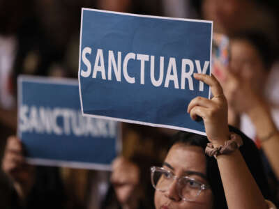 People in the audience hold up signs as the Los Angeles City Council considers a 'sanctuary city' ordinance at City Hall in Los Angeles, California, on November 19, 2024.