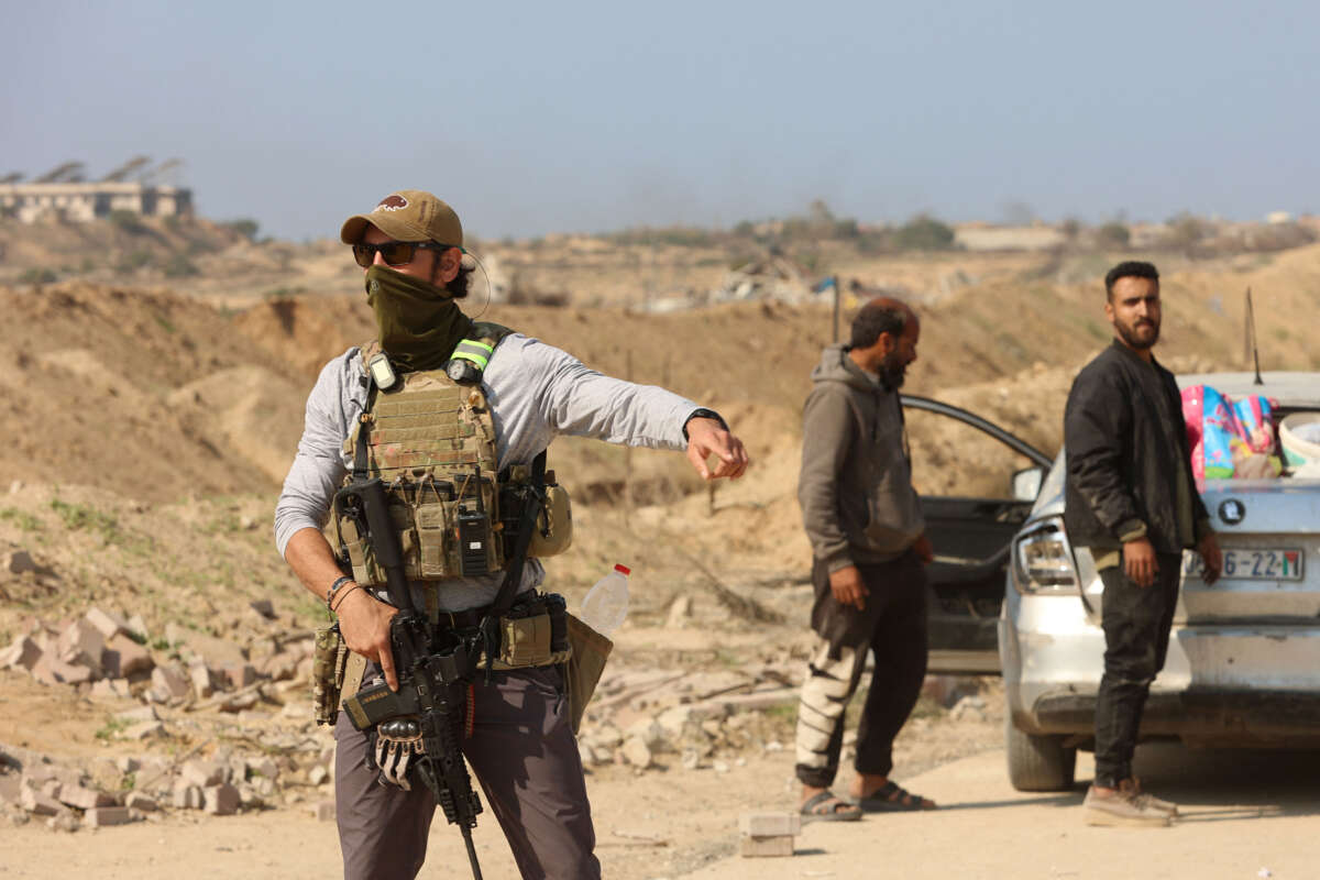 An armed man gestures at a checkpoint manned by US and Egyptian security at the Netzarim corridor as displaced Palestinians make their way from the south to the northern parts of the Gaza Strip, on Salah al-Din road in central Gaza, on January 29, 2025.