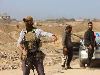 An armed man gestures at a checkpoint manned by US and Egyptian security at the Netzarim corridor as displaced Palestinians make their way from the south to the northern parts of the Gaza Strip, on Salah al-Din road in central Gaza, on January 29, 2025.