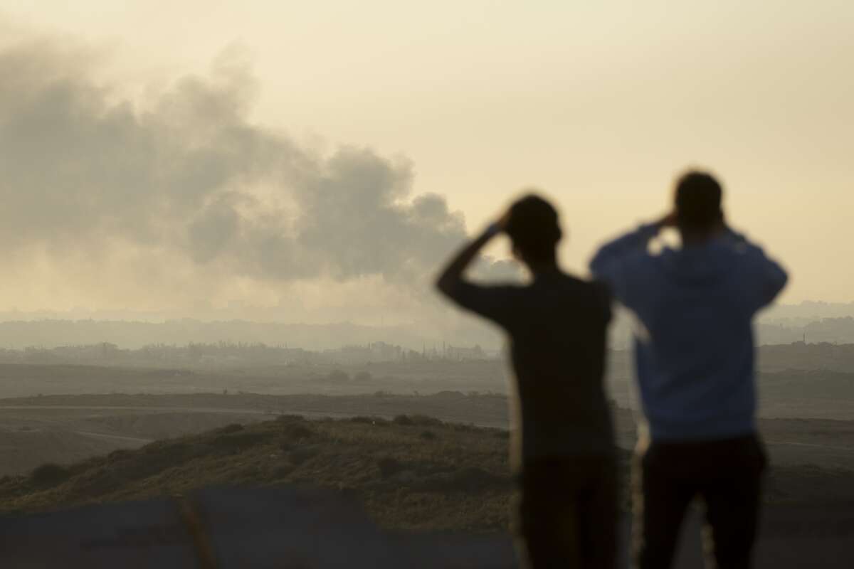 People look at smoke rising over the Gaza Strip as they are standing in a view point in the Israeli southern city on January 13, 2025 in Sderot, Israel.