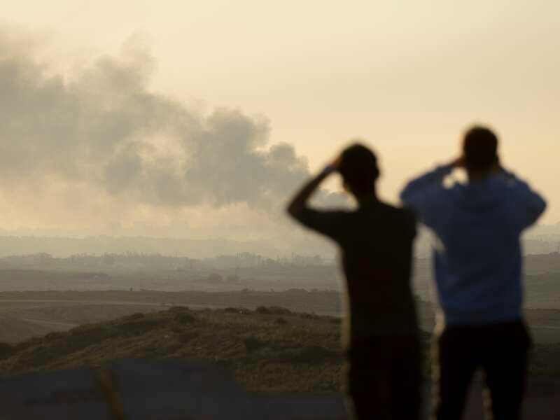 People look at smoke rising over the Gaza Strip as they are standing in a view point in the Israeli southern city on January 13, 2025 in Sderot, Israel.