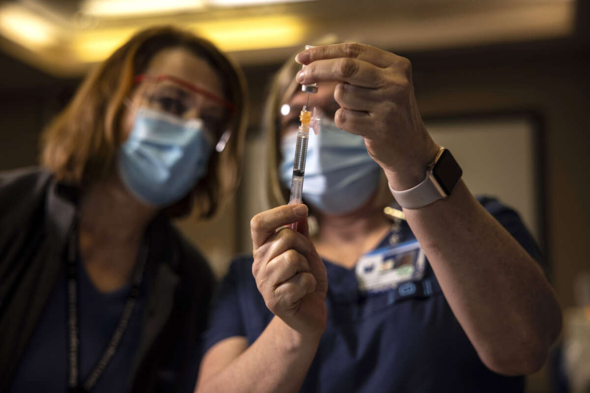 A registered nurse watches as another preps the Pfizer-BioNTech COVID-19 vaccine before shots are administered at a hospital in Portland, Oregon, on December 16, 2020.