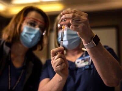 A registered nurse watches as another preps the Pfizer-BioNTech COVID-19 vaccine before shots are administered at a hospital in Portland, Oregon, on December 16, 2020.