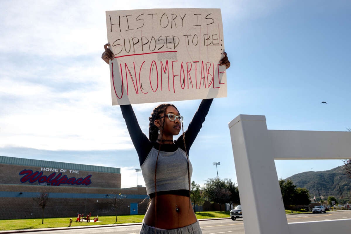 A student holds a sign reading "History is supposed to be uncomfortable" in protest of the district's ban of critical race theory curriculum at Great Oak High School in Temecula, California, on December 16, 2022.