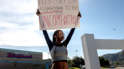 A student holds a sign reading "History is supposed to be uncomfortable" in protest of the district's ban of critical race theory curriculum at Great Oak High School in Temecula, California, on December 16, 2022.