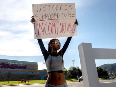 A student holds a sign reading "History is supposed to be uncomfortable" in protest of the district's ban of critical race theory curriculum at Great Oak High School in Temecula, California, on December 16, 2022.