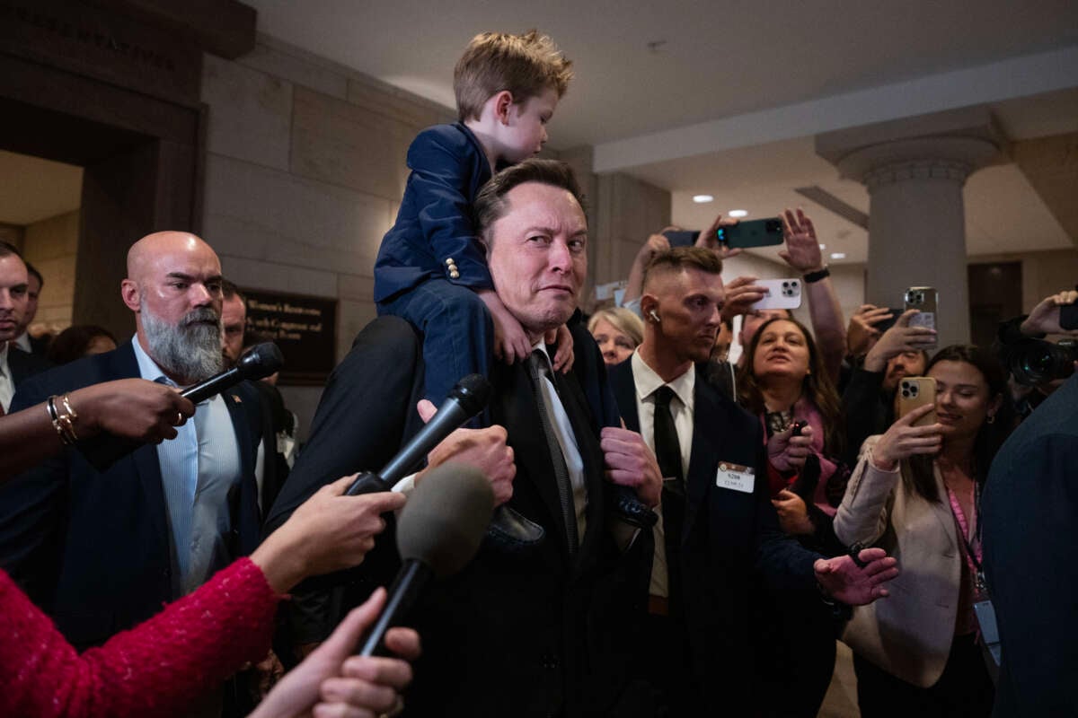 Elon Musk, with his son, makes his way to a meeting in the Capitol Visitor Center with House and Senate Republicans to talk about President-elect Donald Trump's "Department of Government Efficiency," on December 5, 2024, in Washington, D.C. Vivek Ramaswamy also attended.