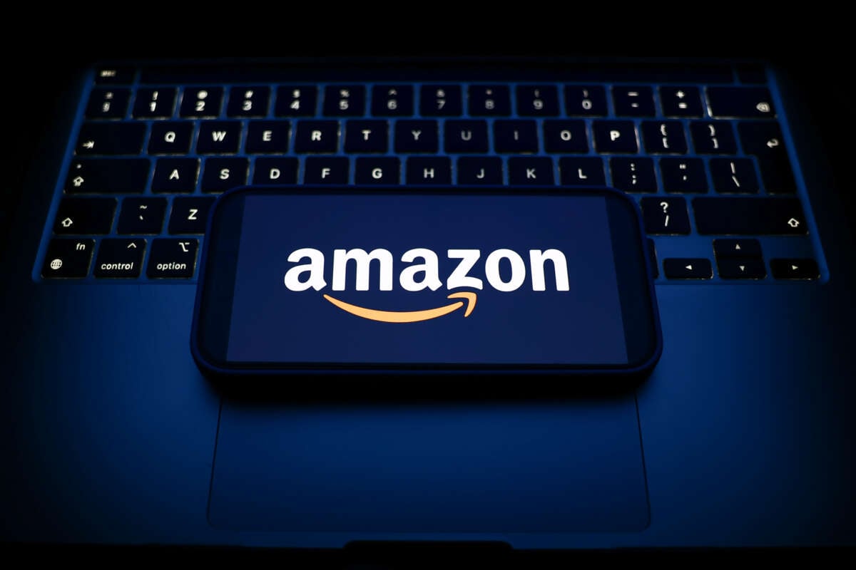 A laptop keyboard and Amazon logo are displayed on a smartphone.