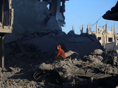 A young Palestinian boy sits amid the rubble in the aftermath of an Israeli strike in the al-Maghazi refugee camp in the central Gaza Strip, on January 3, 2025.