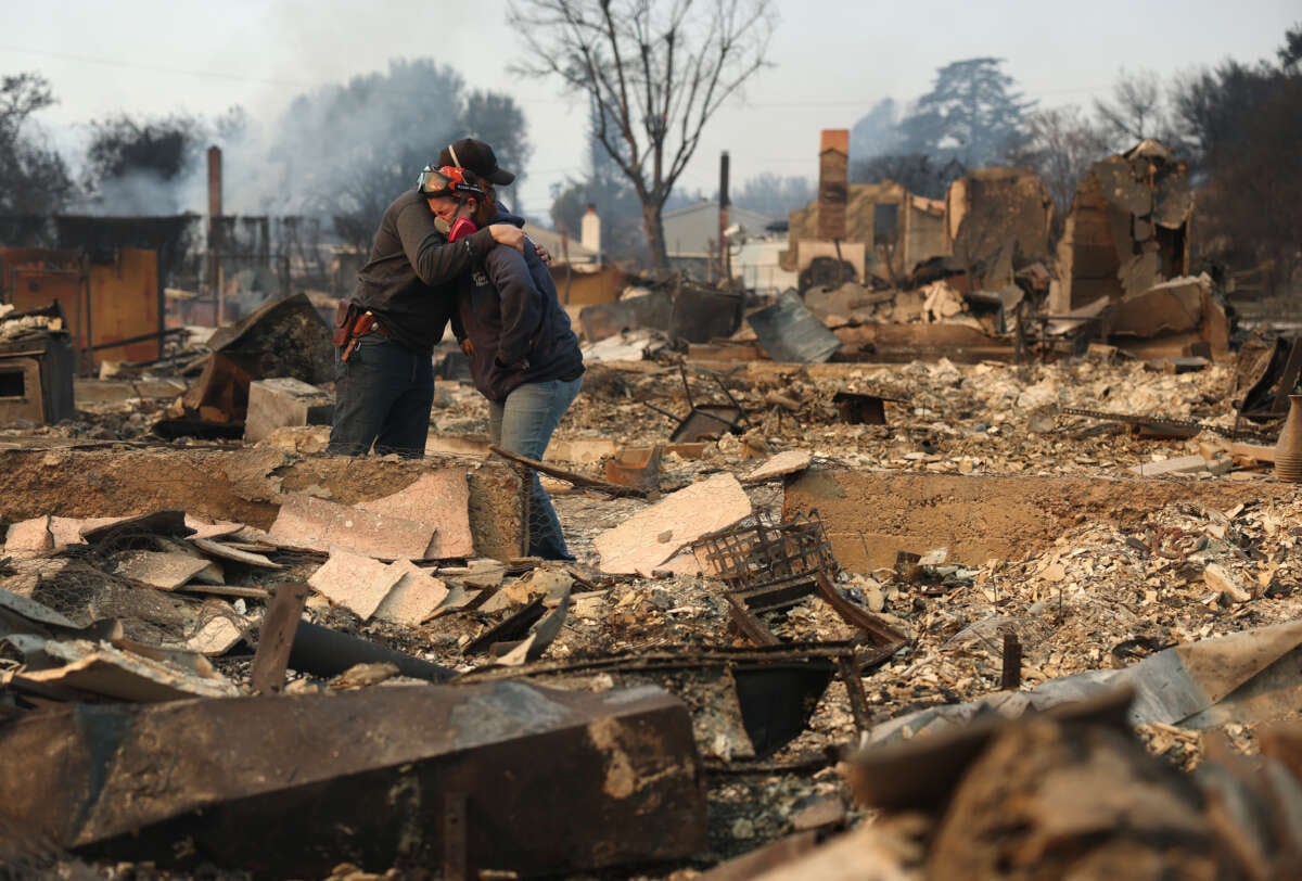 Khaled Fouad (L) and Mimi Laine (R) embrace as they inspect a family member's property that was destroyed by Eaton Fire on January 9, 2025, in Altadena, California.