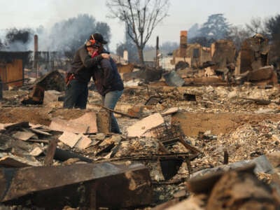 Khaled Fouad (L) and Mimi Laine (R) embrace as they inspect a family member's property that was destroyed by Eaton Fire on January 9, 2025, in Altadena, California.