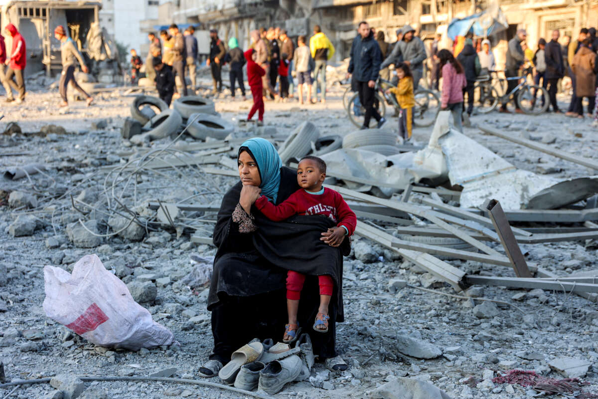 A woman sits with a child and salvaged footwear amid debris and rubble at the site of Israeli bombardment on a residential block in Jalaa Street in Gaza City on January 14, 2025.