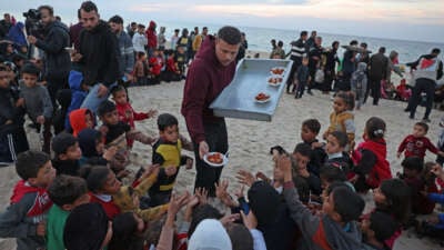 Hamada Shaqoura, a Palestinian man who used to be a food blogger, distributes food to children after cooking a meal for displaced people, in Khan Younis in the southern Gaza Strip on January 16, 2025.