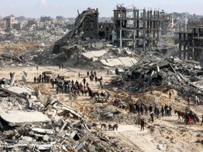 Palestinians walk past the rubble of collapsed buildings along Saftawi street in the Jabalia refugee camp in the northern Gaza Strip on January 20, 2025, a day after a ceasefire deal went into effect.