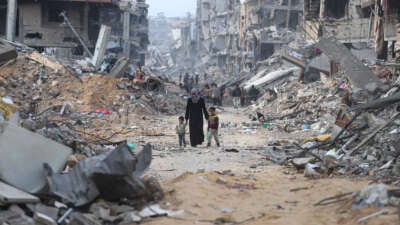 A woman walks along a path through rubble with her children as displaced Palestinians return to northern Gaza to live in tents built on the ruins of their homes, on January 28, 2025, in Gaza, Palestine.