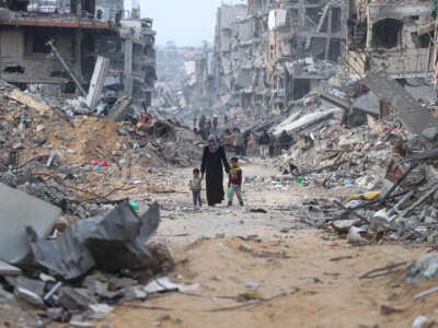 A woman walks along a path through rubble with her children as displaced Palestinians return to northern Gaza to live in tents built on the ruins of their homes, on January 28, 2025, in Gaza, Palestine.