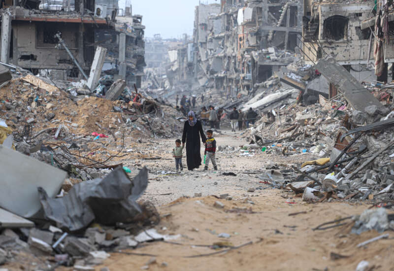 A woman walks along a path through rubble with her children as displaced Palestinians return to northern Gaza to live in tents built on the ruins of their homes, on January 28, 2025, in Gaza, Palestine.