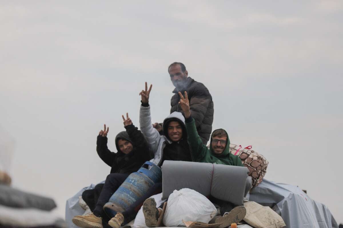 Displaced Palestinians wave as they cross the Netzarim Corridor towards the north following the withdrawal of Israeli troops in central Gaza, on Monday, Febuary 10, 2025.