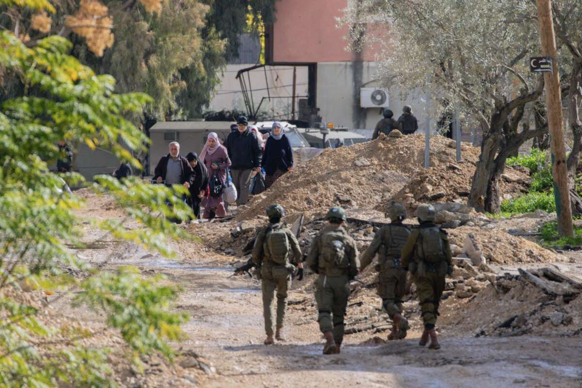 Israeli soldiers walk along a road as displaced Palestinian families evacuate their homes in Jenin, West Bank, on January 23, 2025.