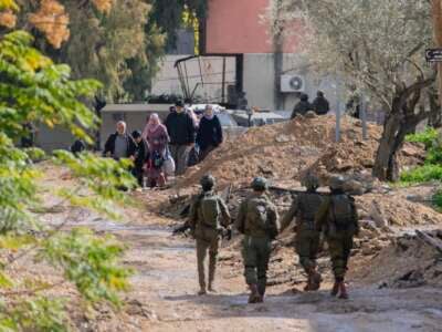 Israeli soldiers walk along a road as displaced Palestinian families evacuate their homes in Jenin, West Bank, on January 23, 2025.