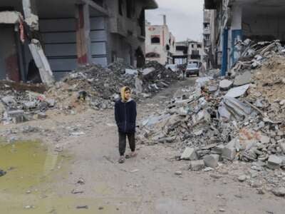 A young boy walks alone through a street filled with rubble and debris, in Gaza City on February 10, 2025.