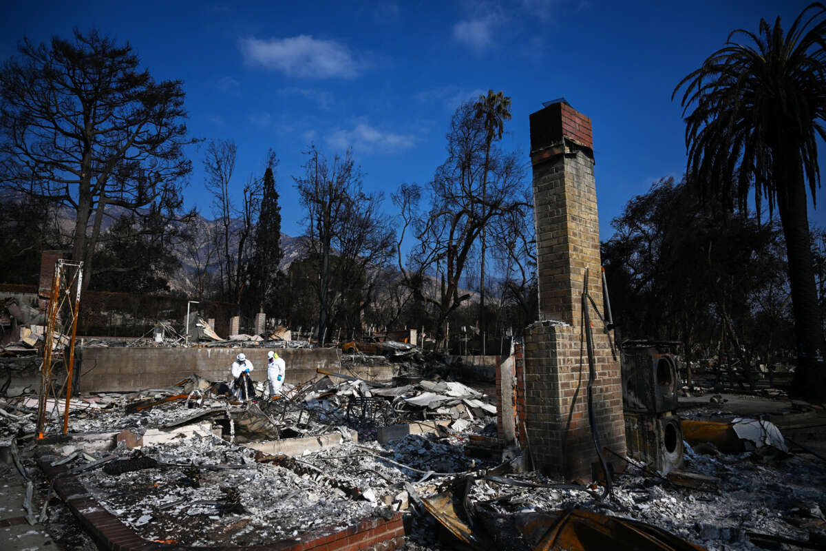 two epa workers in hazmat suits clean burnt debris from the California wildfires