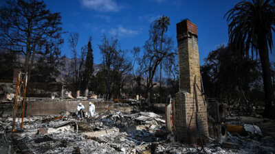 two epa workers in hazmat suits clean burnt debris from the California wildfires