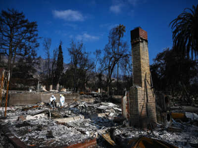 two epa workers in hazmat suits clean burnt debris from the California wildfires