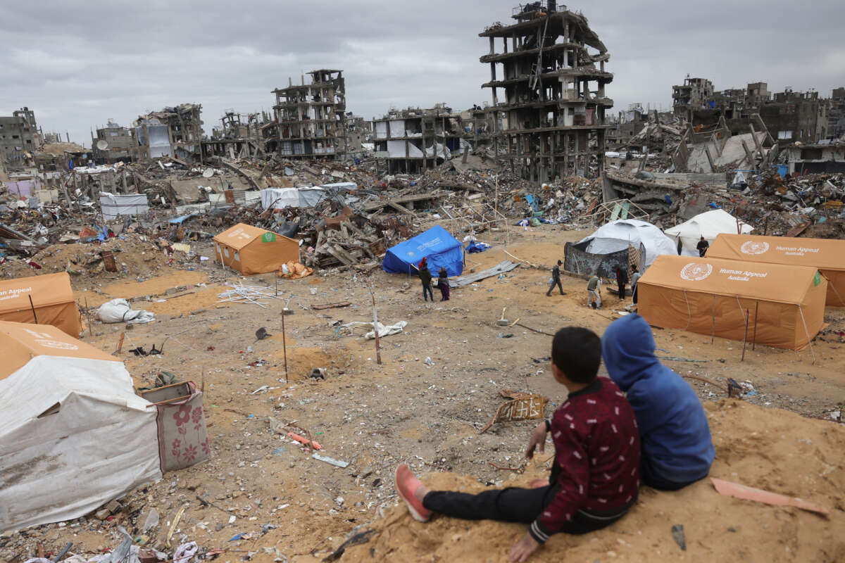 Displaced Palestinian children sit on a sand mound overlooking tents set up amid destroyed buildings in Jabalia in the northern Gaza Strip on February 6, 2025.