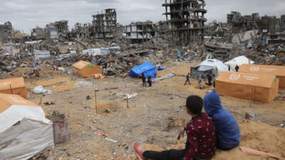 Displaced Palestinian children sit on a sand mound overlooking tents set up amid destroyed buildings in Jabalia in the northern Gaza Strip on February 6, 2025.