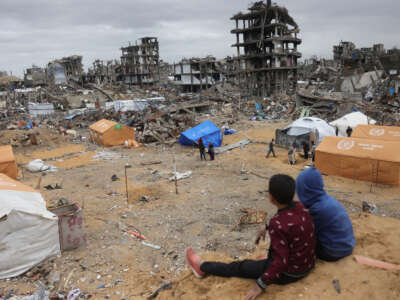 Displaced Palestinian children sit on a sand mound overlooking tents set up amid destroyed buildings in Jabalia in the northern Gaza Strip on February 6, 2025.