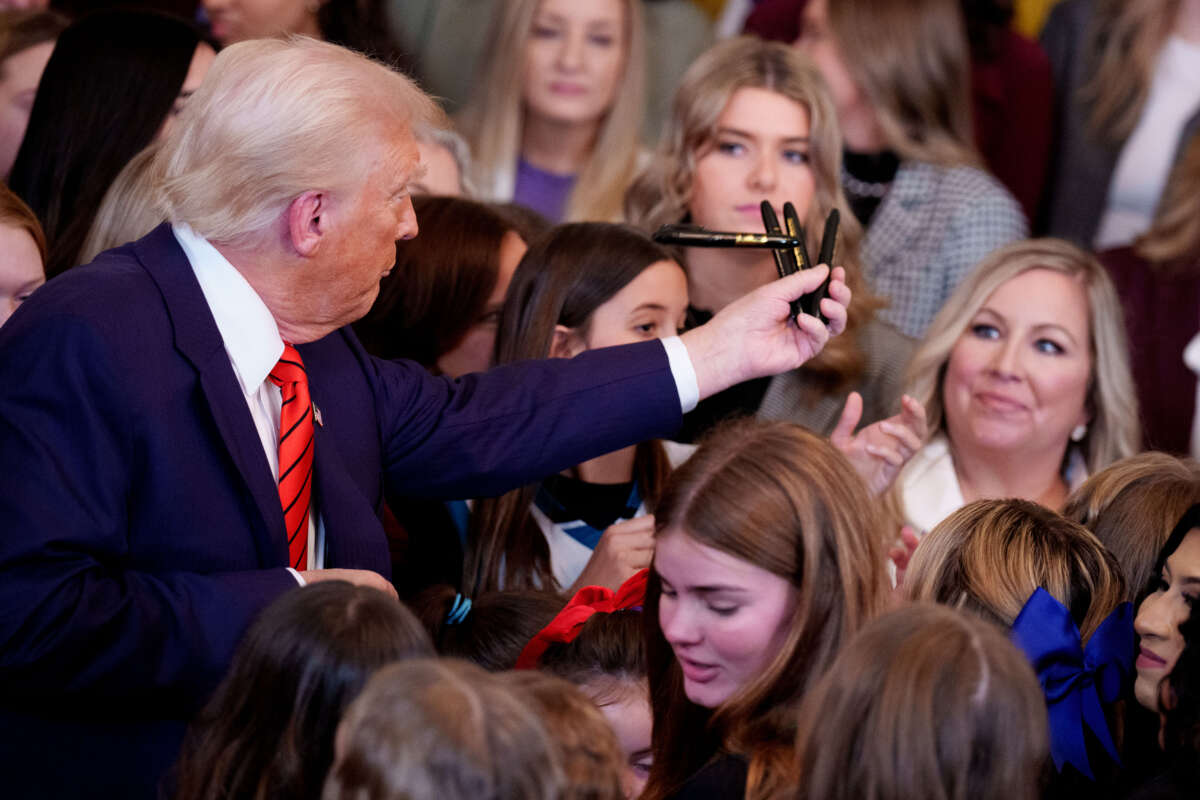 President Donald Trump hands out pens to audience members after signing an executive order banning trans women and girls from women's sports, in the East Room at the White House on February 5, 2025, in Washington, D.C.