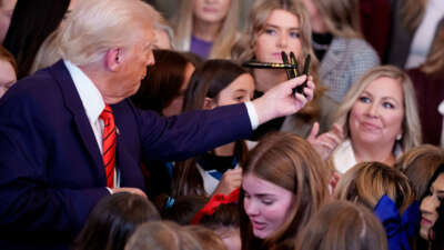 President Donald Trump hands out pens to audience members after signing an executive order banning trans women and girls from women's sports, in the East Room at the White House on February 5, 2025, in Washington, D.C.