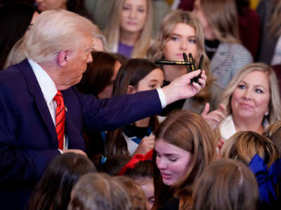 President Donald Trump hands out pens to audience members after signing an executive order banning trans women and girls from women's sports, in the East Room at the White House on February 5, 2025, in Washington, D.C.