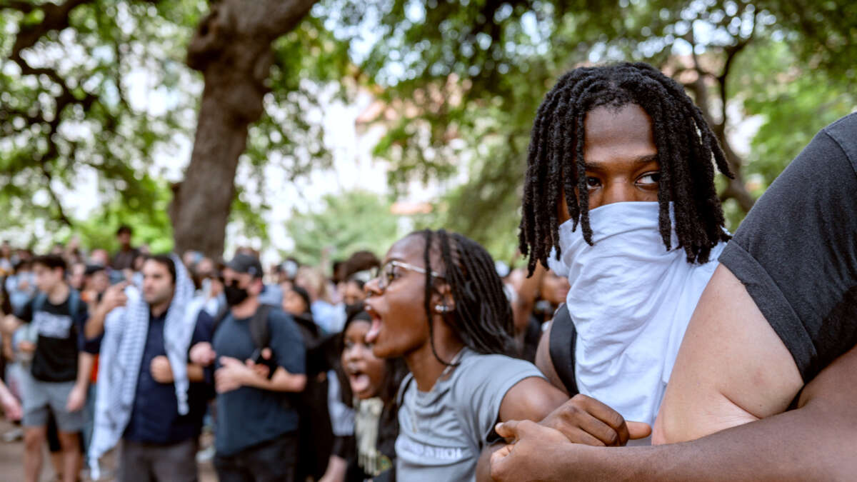 Students of color link arms and chant during an outdoor protest