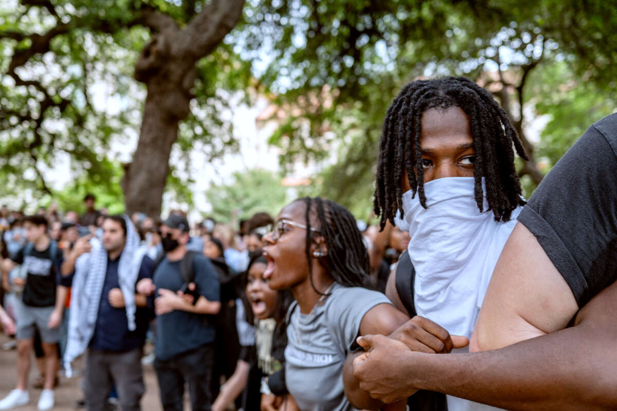 Students of color link arms and chant during an outdoor protest