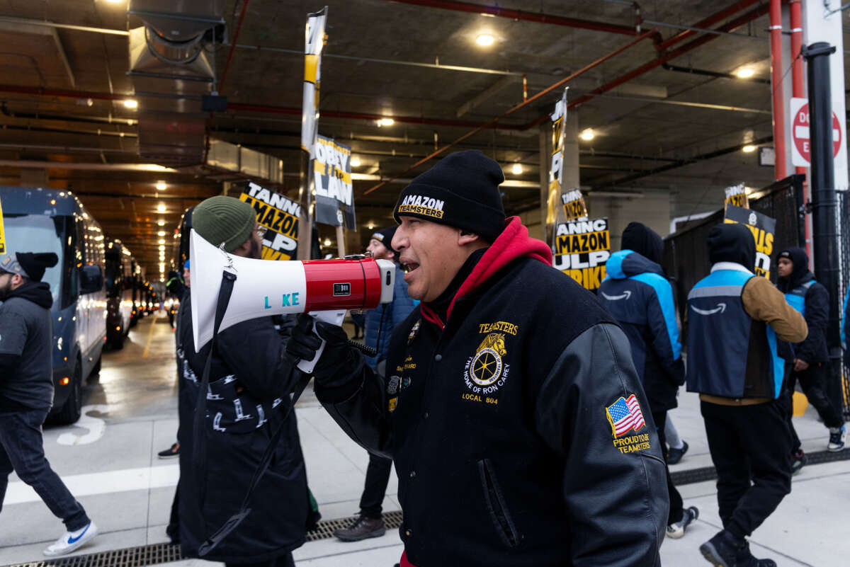 An Amazon teamster chants into a megaphone as other striking workers march around him